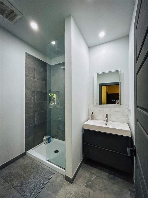 bathroom with tasteful backsplash, a shower stall, visible vents, and baseboards