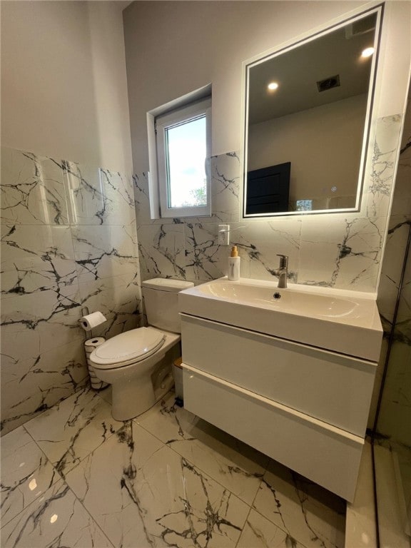 bathroom featuring toilet, visible vents, vanity, tile walls, and marble finish floor