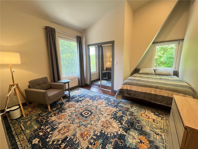 bedroom with multiple windows, baseboards, vaulted ceiling, and wood finished floors