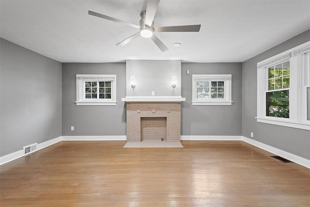 unfurnished living room featuring light hardwood / wood-style flooring, a brick fireplace, and ceiling fan