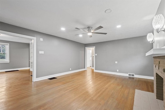 unfurnished living room featuring light hardwood / wood-style floors, a brick fireplace, and ceiling fan