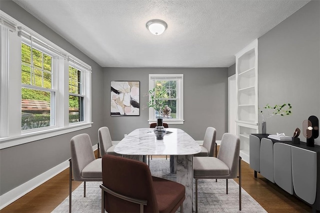 dining area with dark hardwood / wood-style floors, built in features, and a textured ceiling