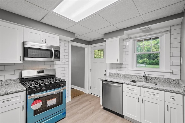 kitchen with sink, light wood-type flooring, a paneled ceiling, and stainless steel appliances