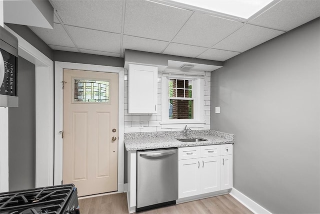 kitchen with appliances with stainless steel finishes, a paneled ceiling, white cabinets, and light hardwood / wood-style floors