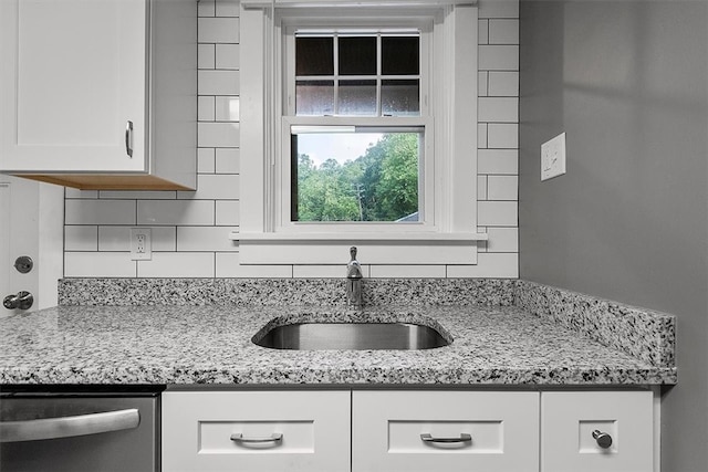 kitchen featuring sink, stainless steel dishwasher, white cabinets, and light stone counters