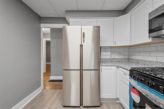 kitchen featuring backsplash, appliances with stainless steel finishes, light hardwood / wood-style floors, and white cabinetry