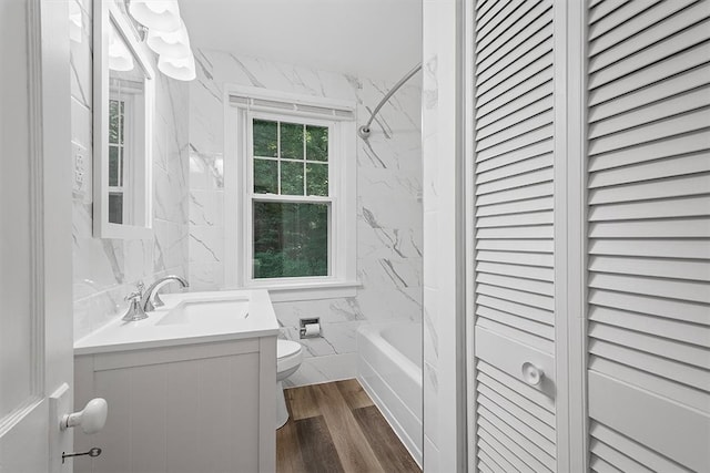 full bathroom with vanity, wood-type flooring, tile walls, shower / tub combination, and toilet