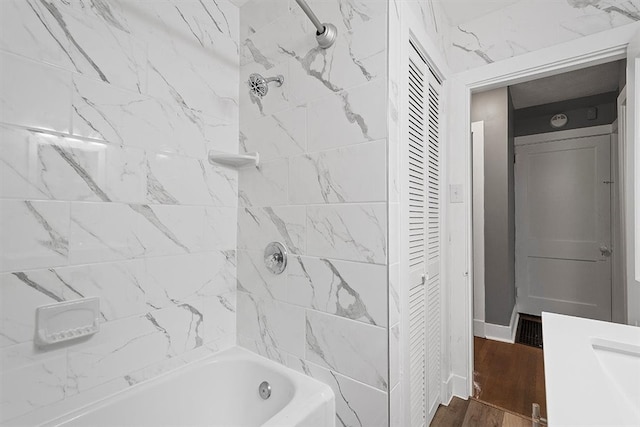 bathroom featuring wood-type flooring, vanity, and tiled shower / bath