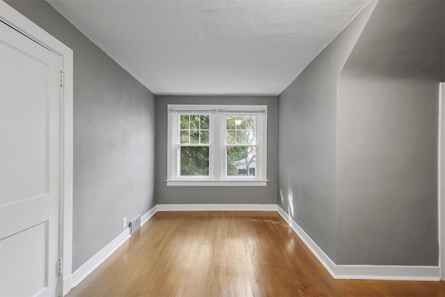 unfurnished room with light hardwood / wood-style flooring and a textured ceiling