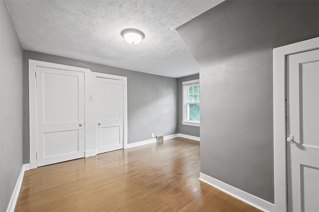 unfurnished bedroom with a textured ceiling and hardwood / wood-style floors