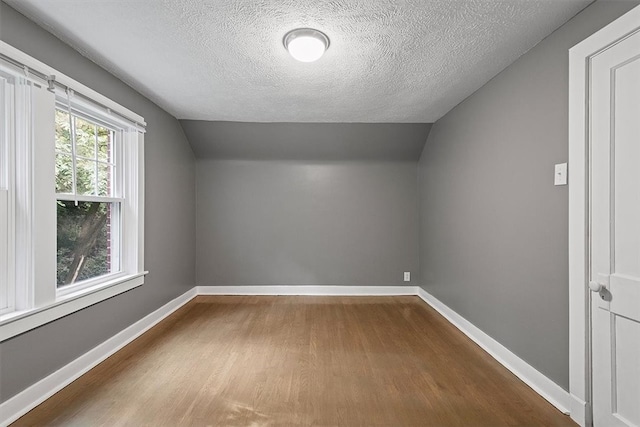 bonus room featuring a textured ceiling, lofted ceiling, and hardwood / wood-style flooring