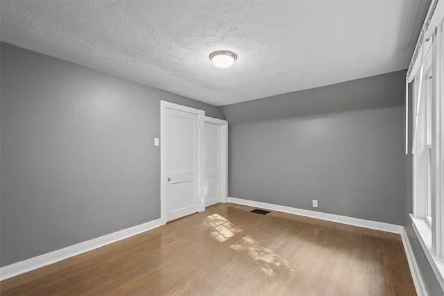 interior space with lofted ceiling, a closet, light wood-type flooring, and a textured ceiling