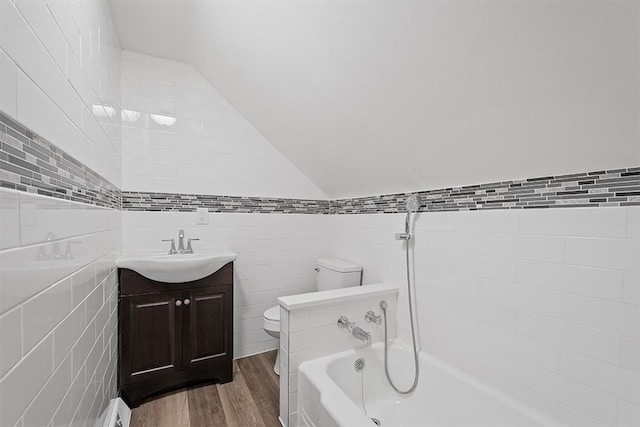 full bathroom featuring lofted ceiling, toilet, vanity, tile walls, and hardwood / wood-style flooring