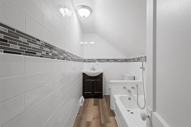 full bathroom with vanity, hardwood / wood-style flooring, tile walls, toilet, and lofted ceiling