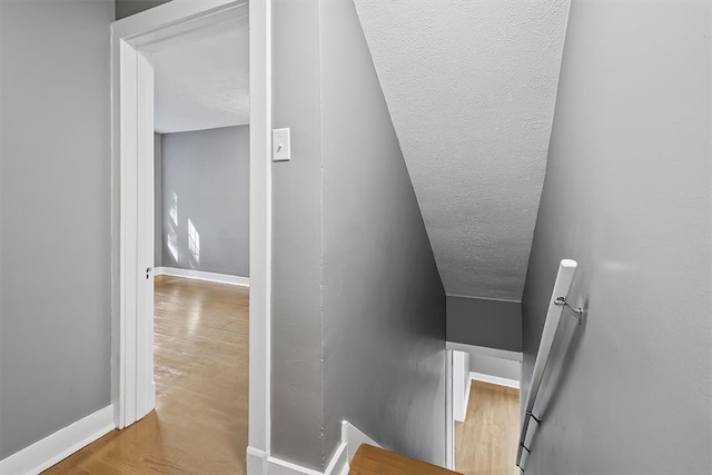 stairway featuring a textured ceiling and hardwood / wood-style flooring