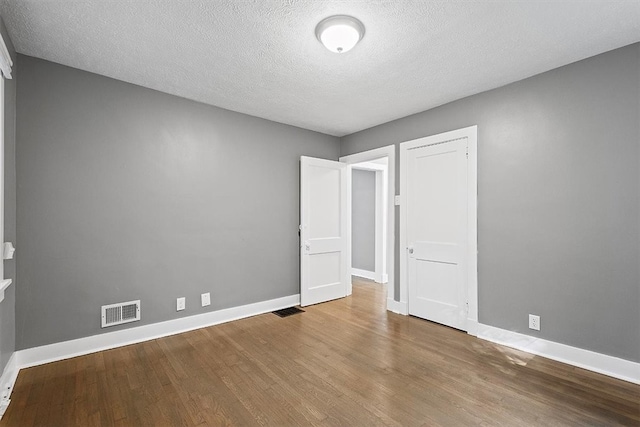 spare room with a textured ceiling and hardwood / wood-style floors