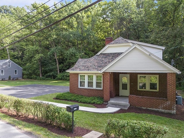 view of front of house with cooling unit and a front lawn