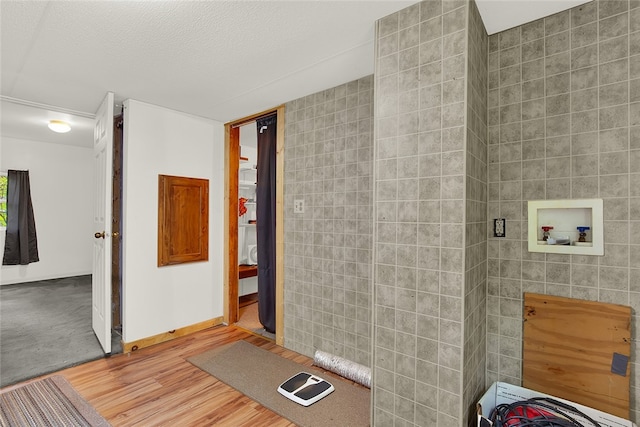 bathroom with tile walls, wood-type flooring, and a textured ceiling