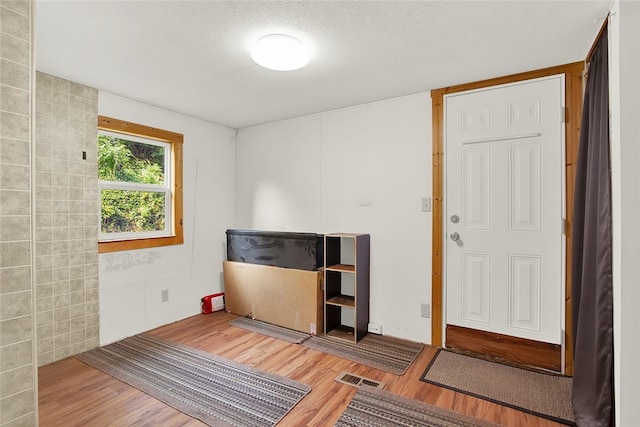 interior space with hardwood / wood-style flooring, a textured ceiling, and tile walls