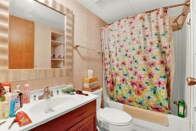 full bathroom with vanity, tile walls, shower / tub combo, toilet, and a textured ceiling