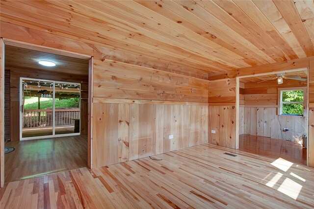 unfurnished room with wood ceiling, wood walls, ceiling fan, and light hardwood / wood-style floors