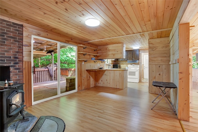 unfurnished living room featuring wood ceiling, wood walls, light wood-type flooring, and a wood stove