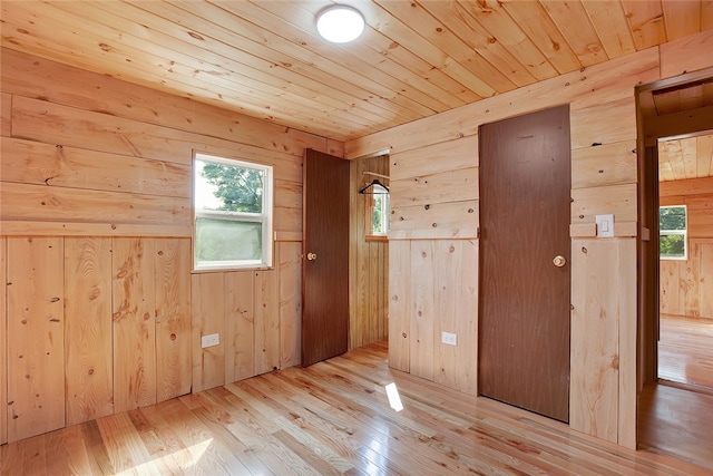 spare room featuring wooden walls, wooden ceiling, and light hardwood / wood-style flooring