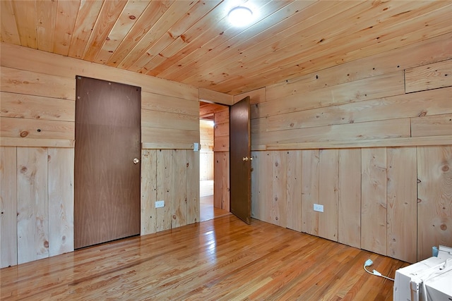 interior space with wood walls, washing machine and dryer, light wood-type flooring, and wood ceiling