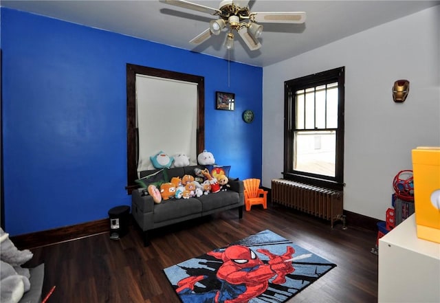 interior space with dark wood-type flooring, radiator heating unit, and ceiling fan