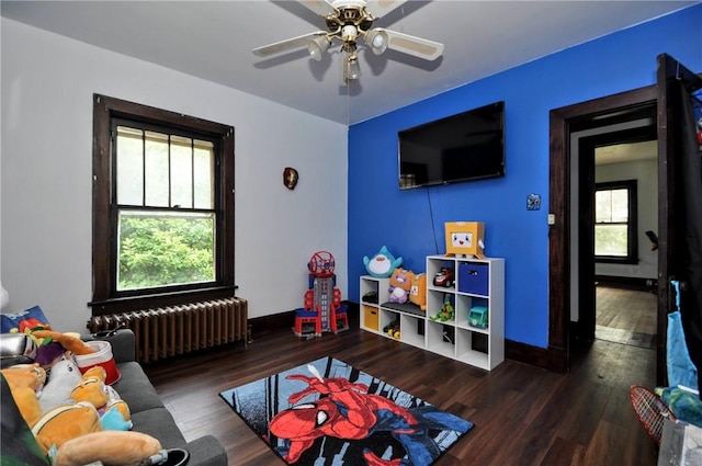 game room featuring dark hardwood / wood-style flooring, radiator, a wealth of natural light, and ceiling fan