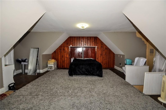 bedroom featuring vaulted ceiling and wood walls