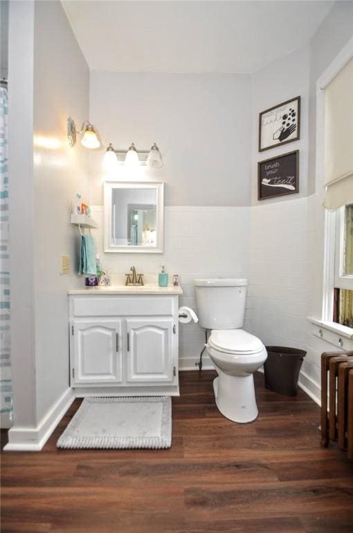 bathroom with hardwood / wood-style flooring, vanity, radiator, and toilet