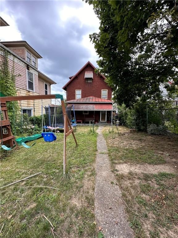 back of house with a playground and a trampoline