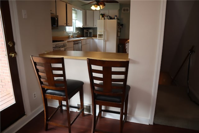 kitchen with black microwave, dark hardwood / wood-style floors, stove, white fridge with ice dispenser, and ceiling fan