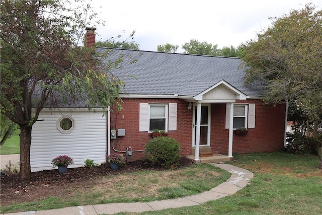 view of front of home featuring brick siding, a front yard, a shingled roof, and a chimney