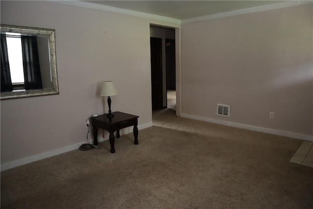 spare room with carpet flooring, visible vents, baseboards, and crown molding
