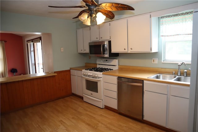 kitchen with stainless steel appliances, light hardwood / wood-style floors, sink, white cabinets, and ceiling fan