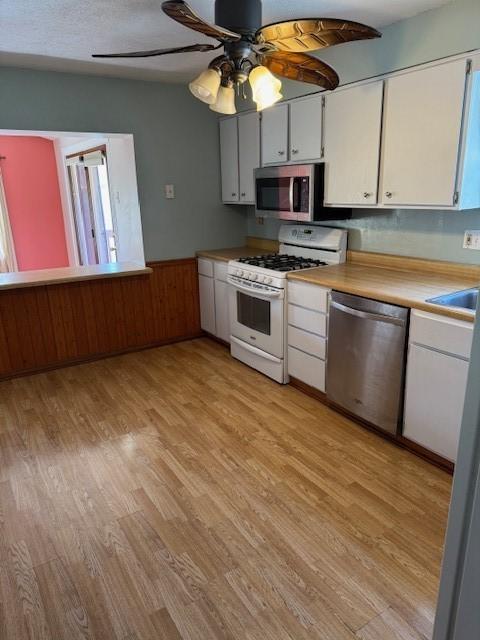 kitchen with white cabinets, light countertops, light wood-type flooring, ceiling fan, and stainless steel appliances