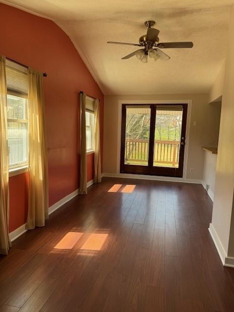 spare room with dark wood finished floors, a ceiling fan, baseboards, and lofted ceiling