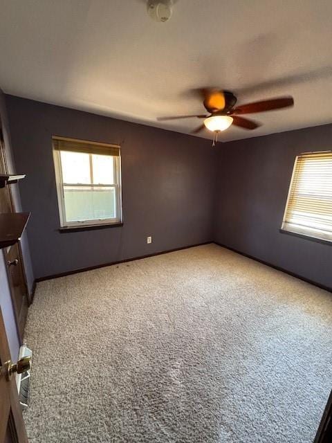 carpeted spare room with a ceiling fan