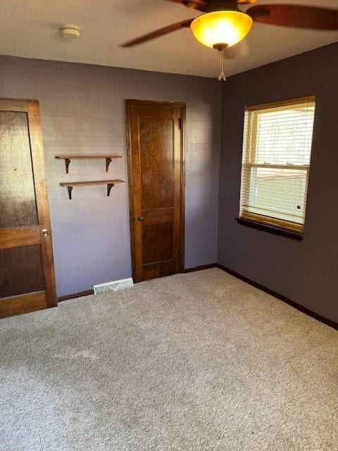 empty room with light carpet, ceiling fan, baseboards, and visible vents