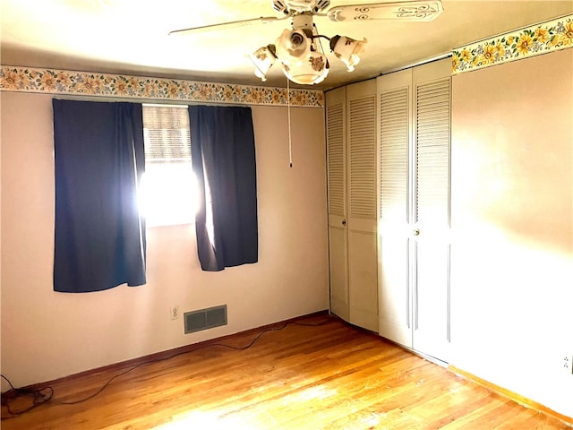 unfurnished bedroom featuring ceiling fan, a closet, and hardwood / wood-style flooring