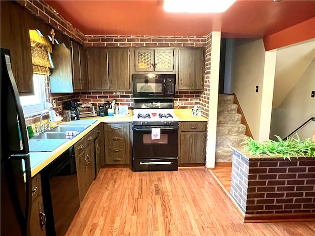 kitchen with black appliances, sink, dark brown cabinetry, and light hardwood / wood-style floors