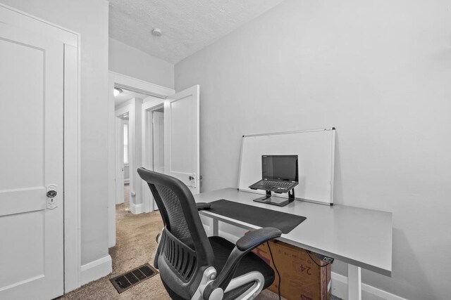 carpeted home office with a textured ceiling