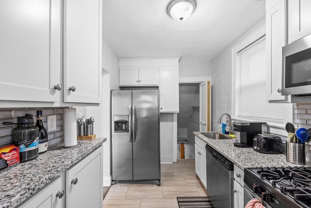 kitchen featuring sink, white cabinetry, light stone countertops, and stainless steel appliances