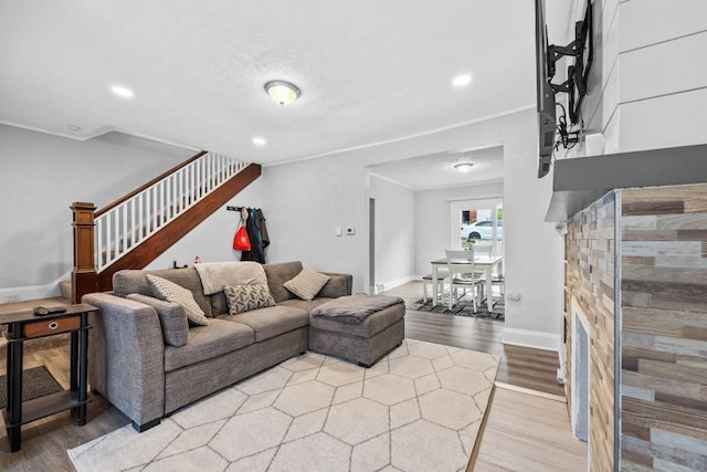 living room featuring a fireplace, light wood-type flooring, and crown molding