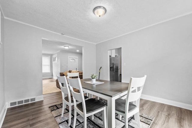 dining area with ornamental molding, a textured ceiling, and hardwood / wood-style floors