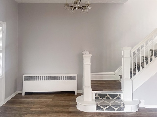 stairway featuring hardwood / wood-style floors, a notable chandelier, and radiator