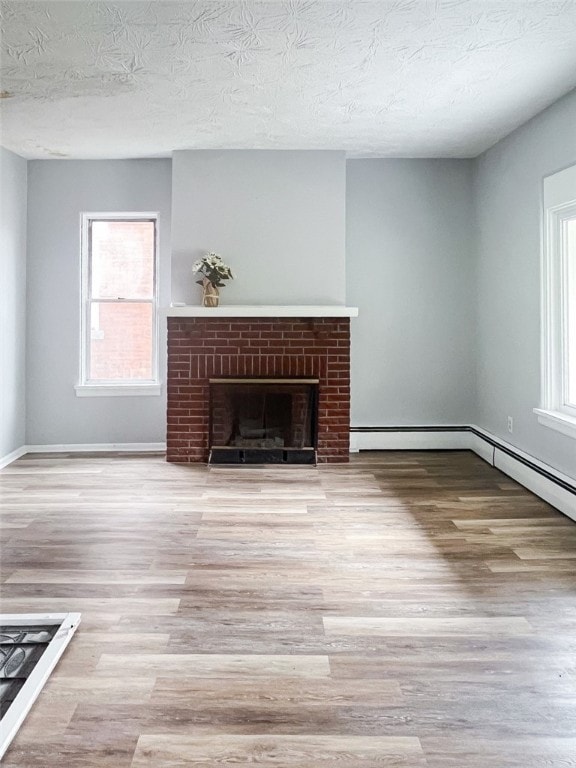 unfurnished living room with a textured ceiling, a brick fireplace, and hardwood / wood-style floors