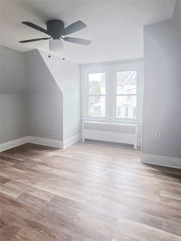 bonus room featuring light hardwood / wood-style floors, radiator, and ceiling fan